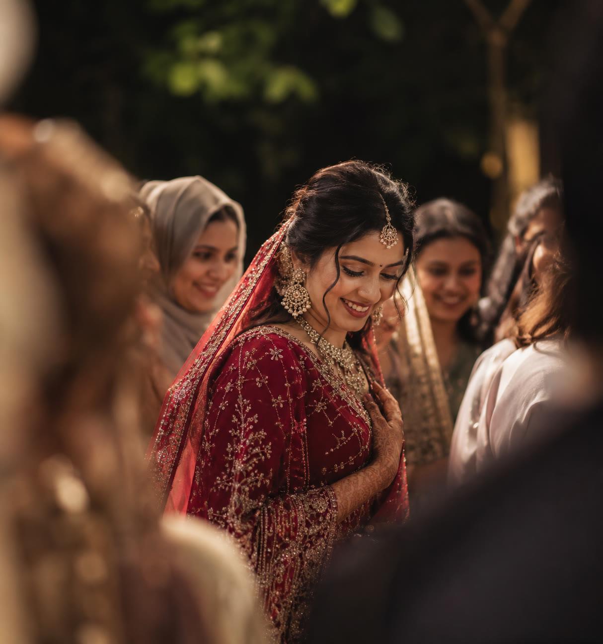 A bride in red laughing with the women of her family